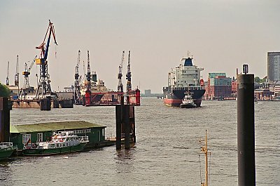 Et stort containerskib trækkes til kaj af et par slæbebåde